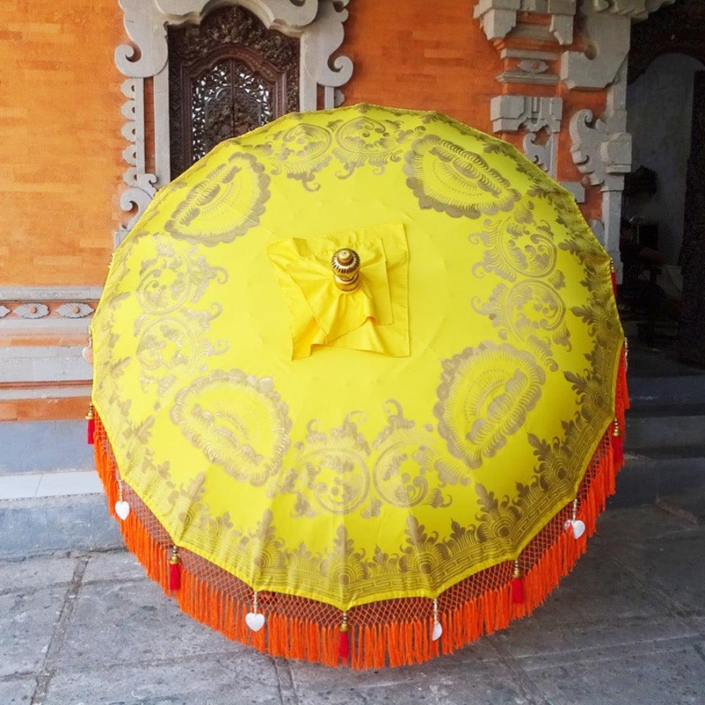 Arabella Parasol in vibrant yellow with gold hand-painted details and orange fringes, perfect for elegant outdoor spaces.